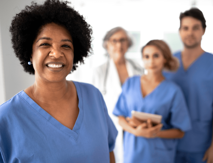 A nurse in blue scrubs smiling.